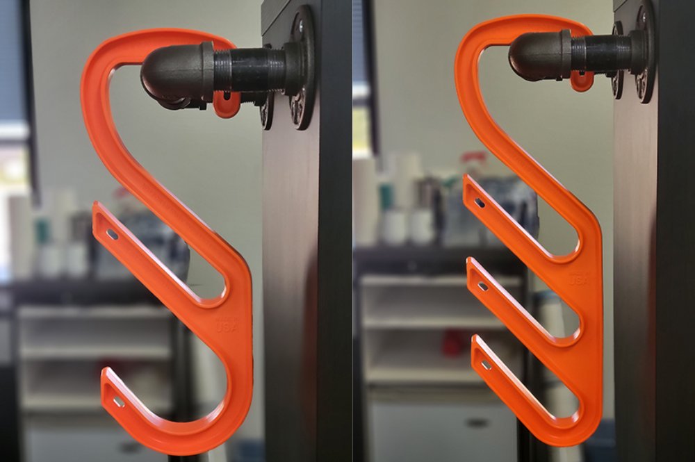 Two bright orange safety hooks hanging on round pipe.