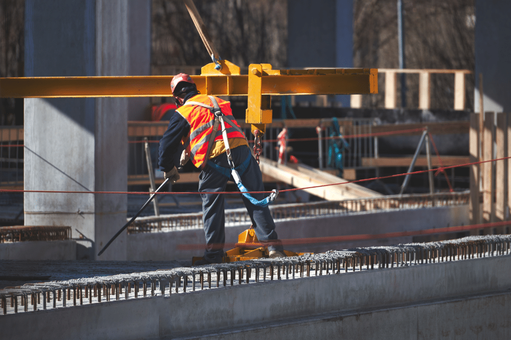 A construction worker in safety gear diligently works on a concrete structure, ensuring safety and precision in the task.